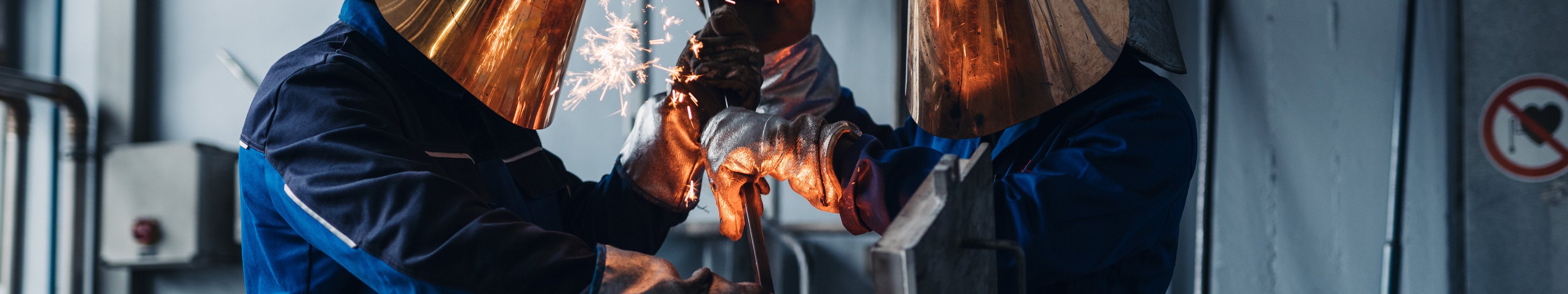 Zwei Personen arbeiten an einer Gießanlage wo Funken sprühen