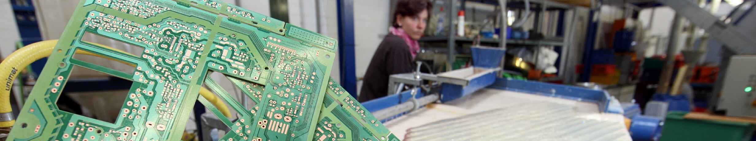 Platinen die neben einer Recyclinganlage ins Bild gehalten werden