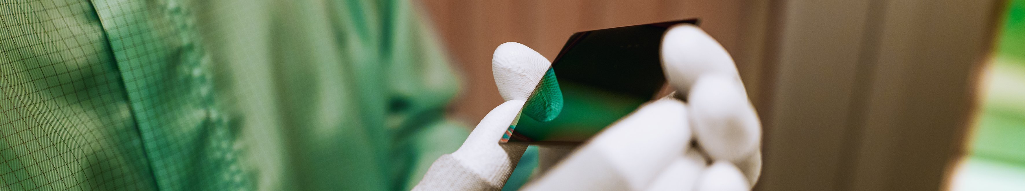 Zwei Hände mit Handschuhen halten eine kleine Glasplatte